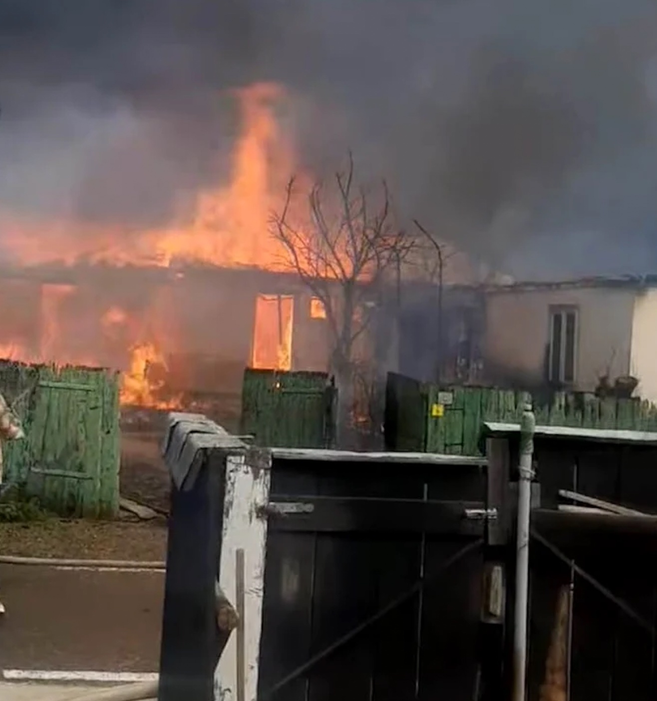 Casă cuprinsă de flăcări în spatele gardului